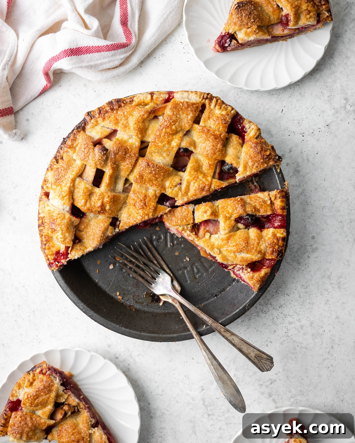 A sliced gluten free apple cranberry pie on a white table.