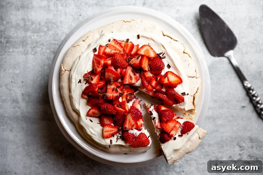 Pavlova with dark chocolate and strawberries on a cake stand with a cake server alongside.