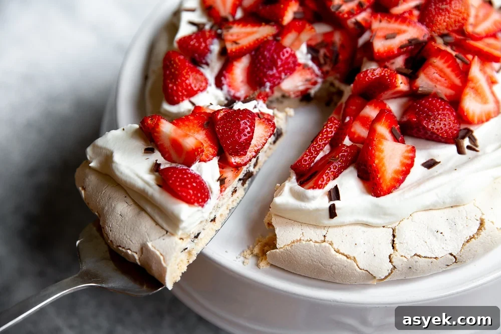 Close up of a slice of pavlova with dark chocolate, topped with whipped cream and strawberries.