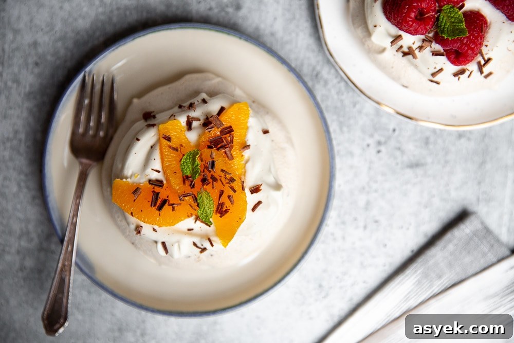 Overhead shot of a pavlova on a plate, topped with orange segments and chocolate.