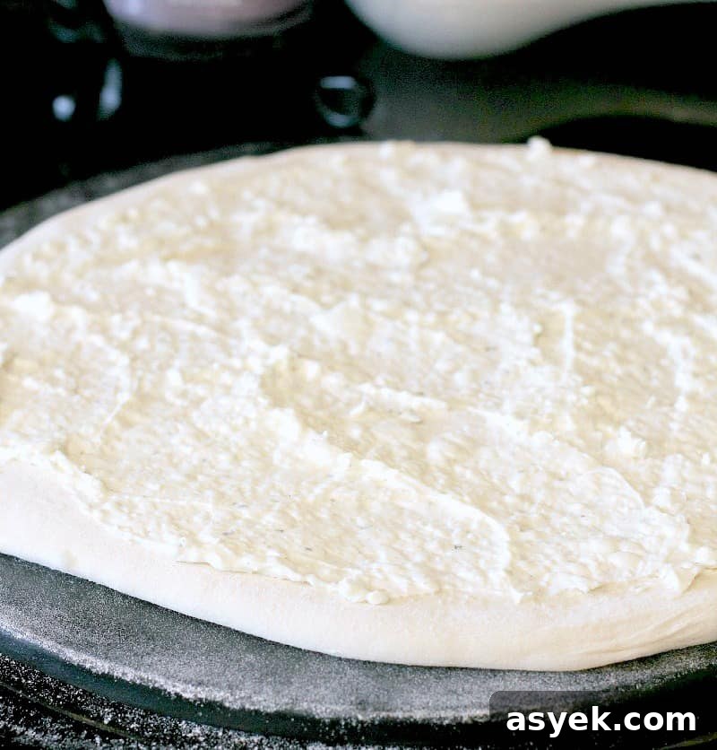 Jalapeno Popper Pizza Recipe with Cream Cheese Filling 4 pizza dough rolled out on a stone, topped with the cream cheese sauce, the basis for the jalapeno cheese dip of this pizza