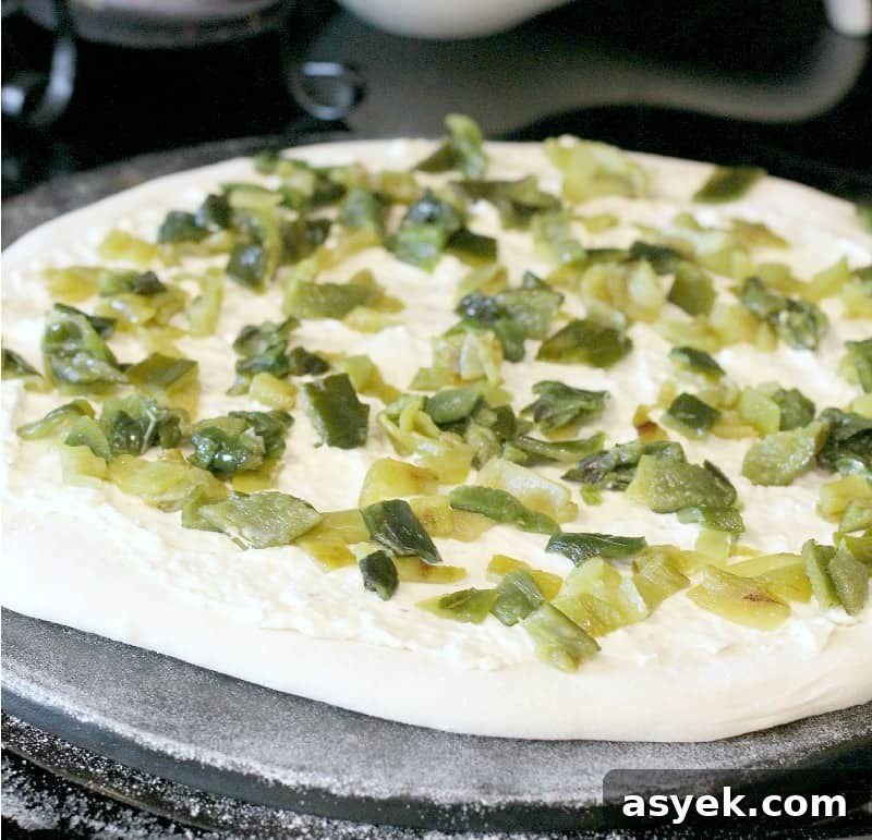 Jalapeno Popper Pizza Recipe with Cream Cheese Filling 5 pizza dough rolled out on a stone, topped with sauce and peppers