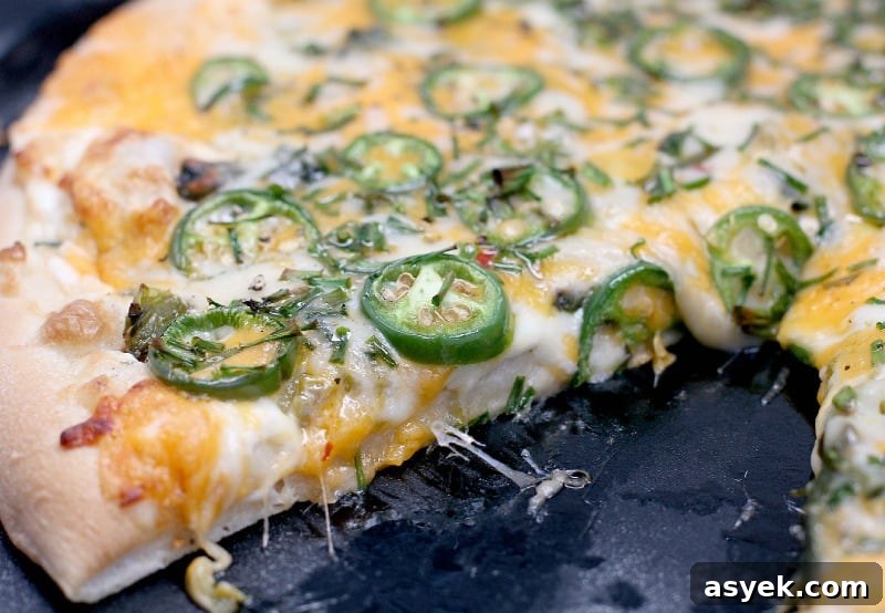 Jalapeno Popper Pizza Recipe with Cream Cheese Filling 7 side view of the finished jalapeno pizza, sliced to show the cooked toppings and melty cheese