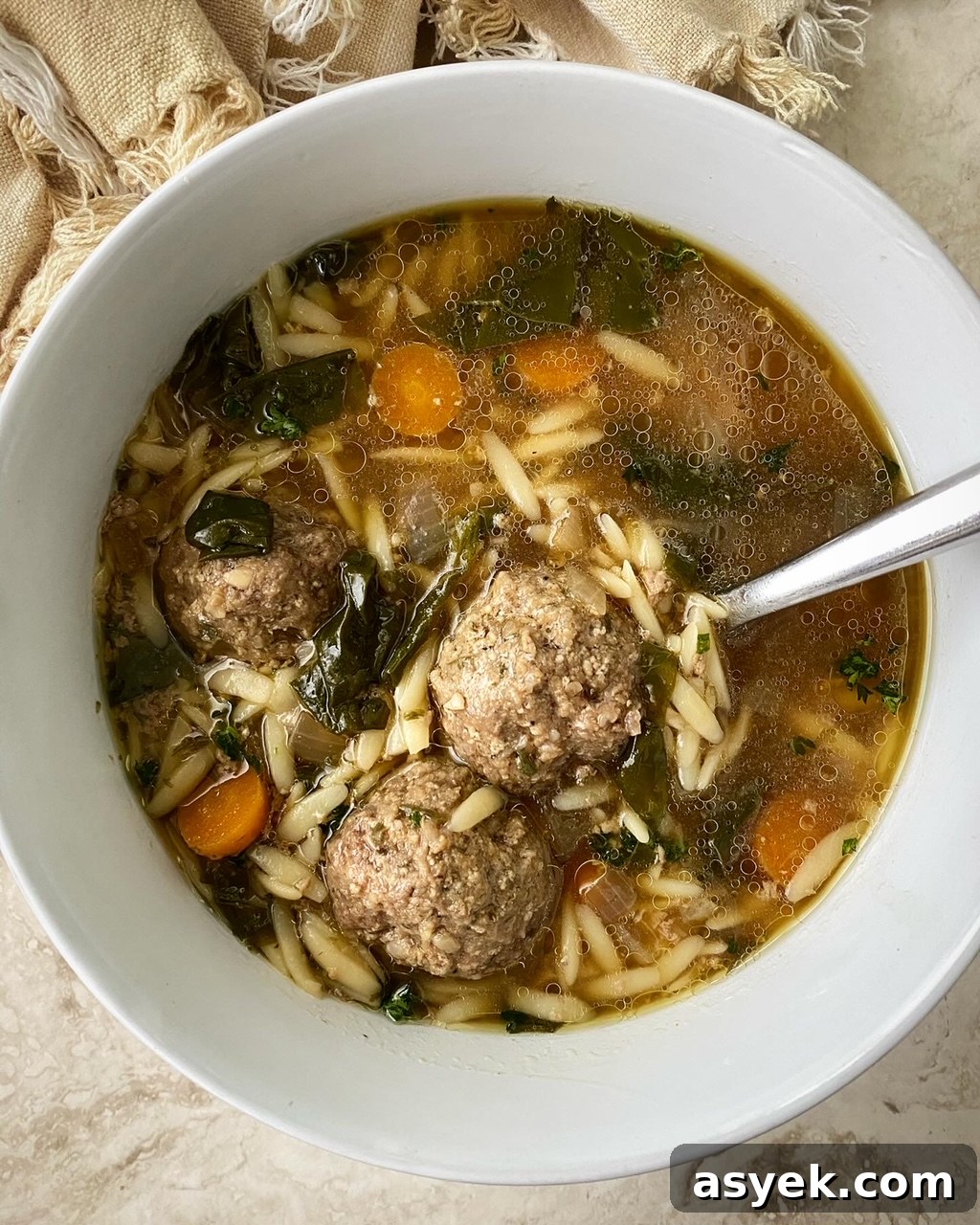 Italian wedding soup in a white bowl with a spoon