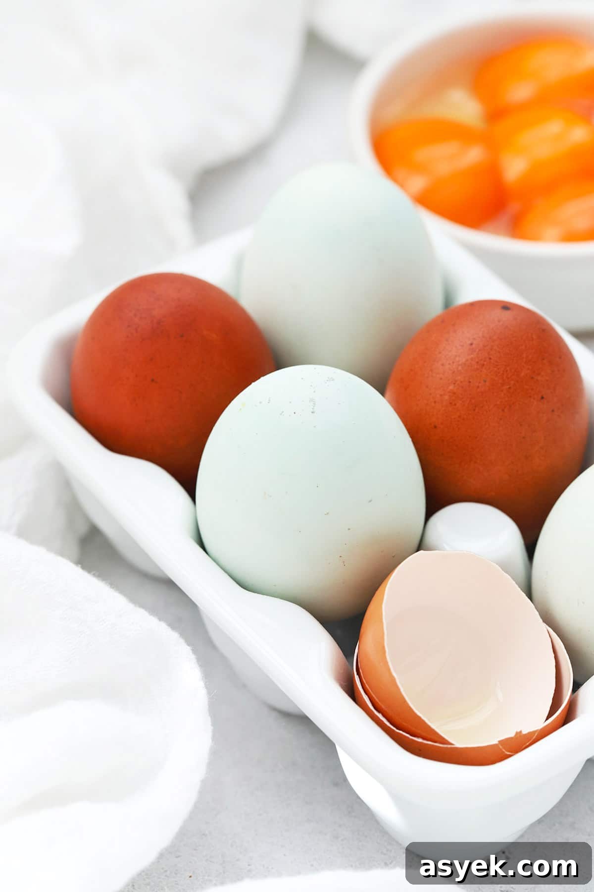 Front view of colorful farm eggs in a white egg carton