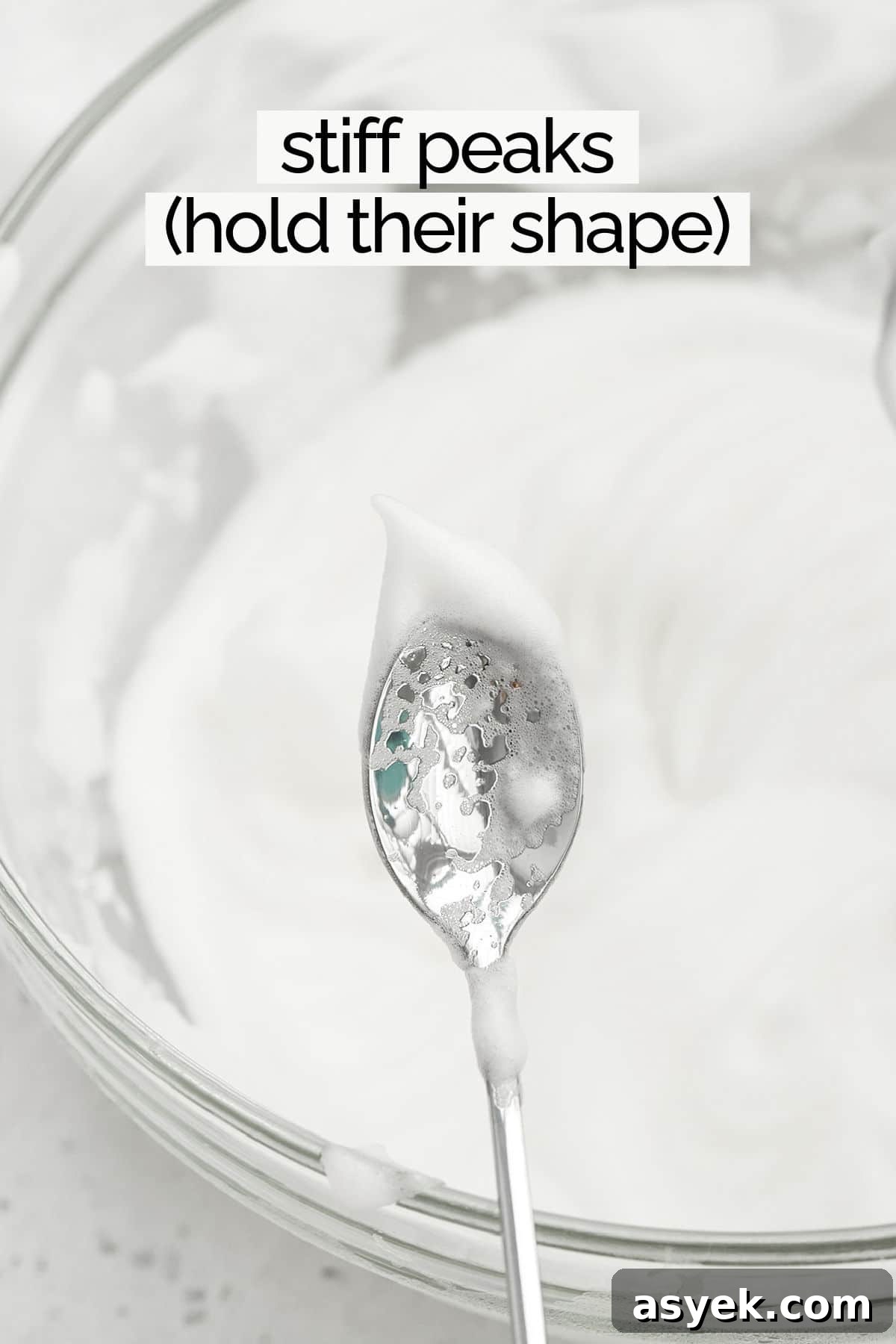 Egg whites whipped to stiff peaks on the end of a spoon