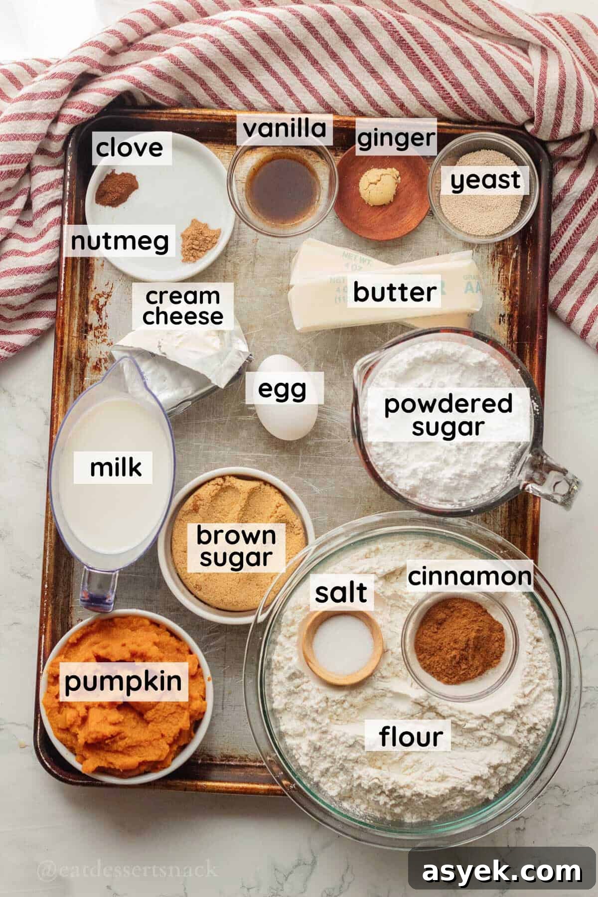 Homemade Pumpkin Cinnamon Rolls with Maple Glaze 3 Ingredients for pumpkin cinnamon rolls labeled in glass bowls on metal baking sheet.