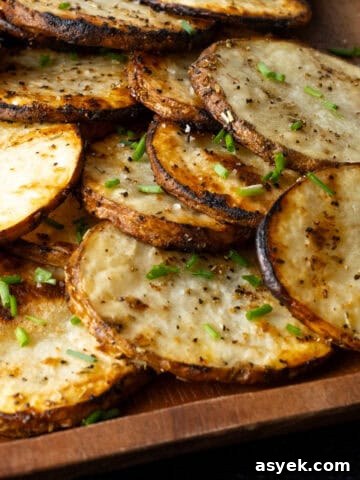 Stack of sliced thinly grilled potatoes on wooden serving platter.