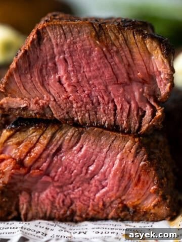 Grilled filet mignon steak cut in half and stacked on itself showing medium rare cook.