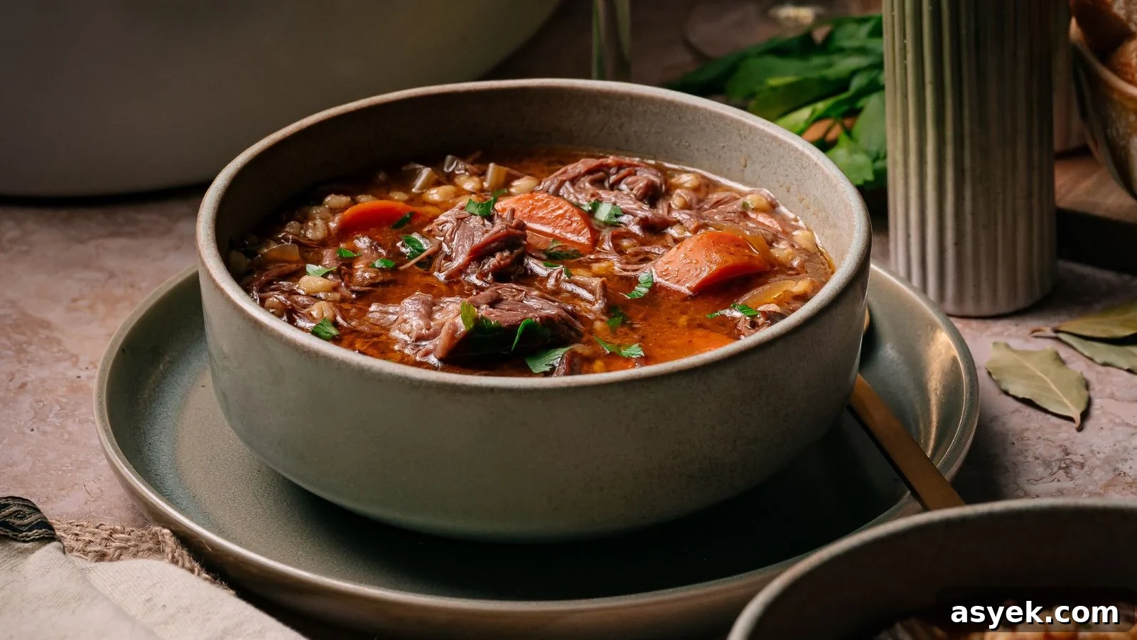 Hearty slow-cooked beef and barley soup filled with tender short rib pieces in a deep bowl.