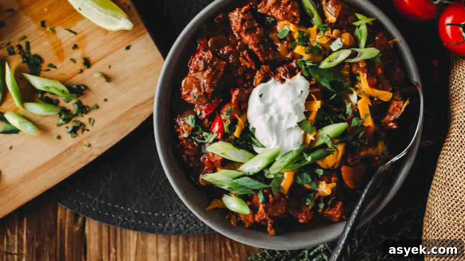 Smoked brisket chili topped with onions and herbs served hot in a cast iron bowl.