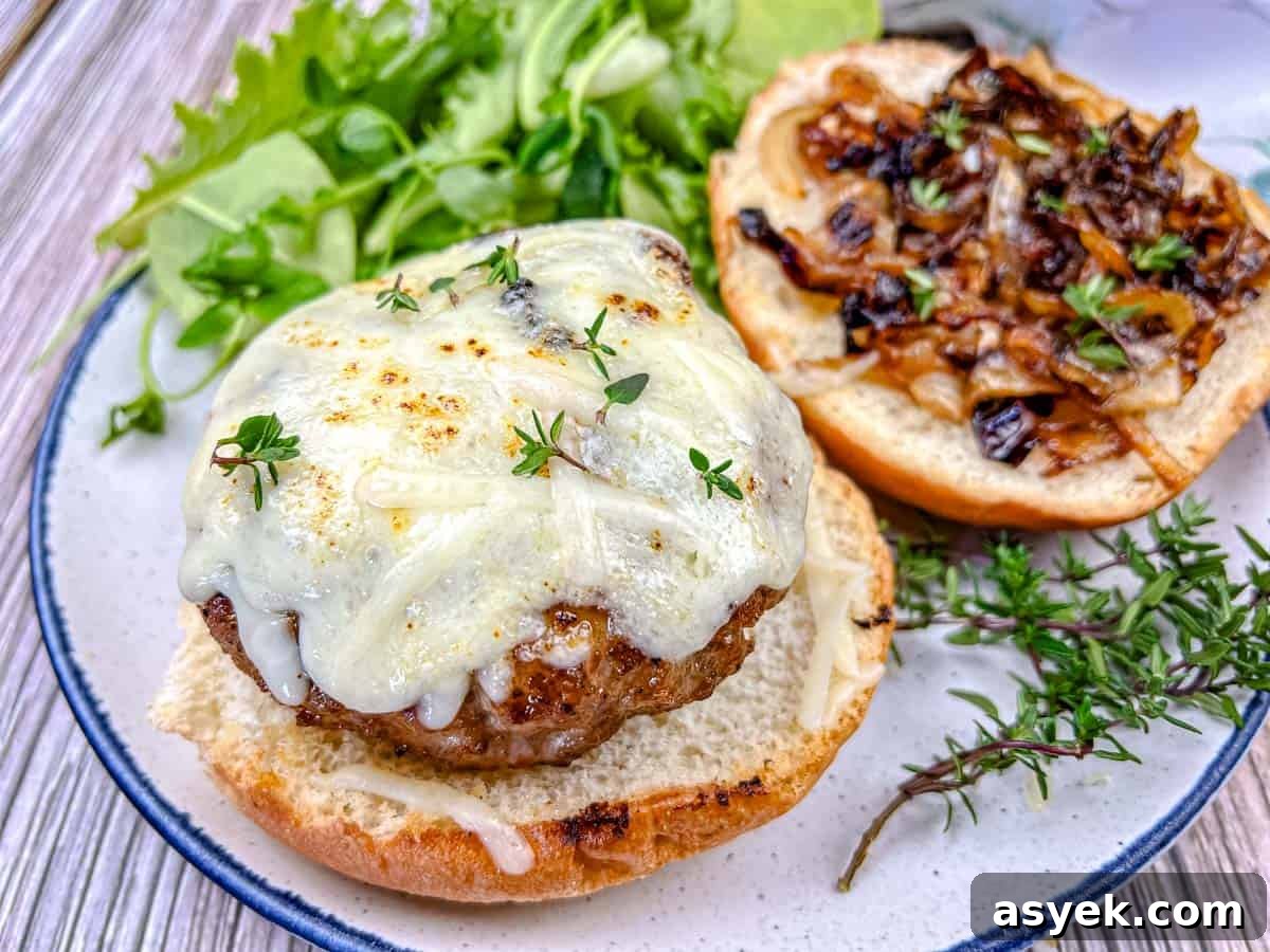 Close-up shot of Grilled French Onion Pork Burgers on a Ninja Woodfire Outdoor Grill topped with cheesy onion on a plate.