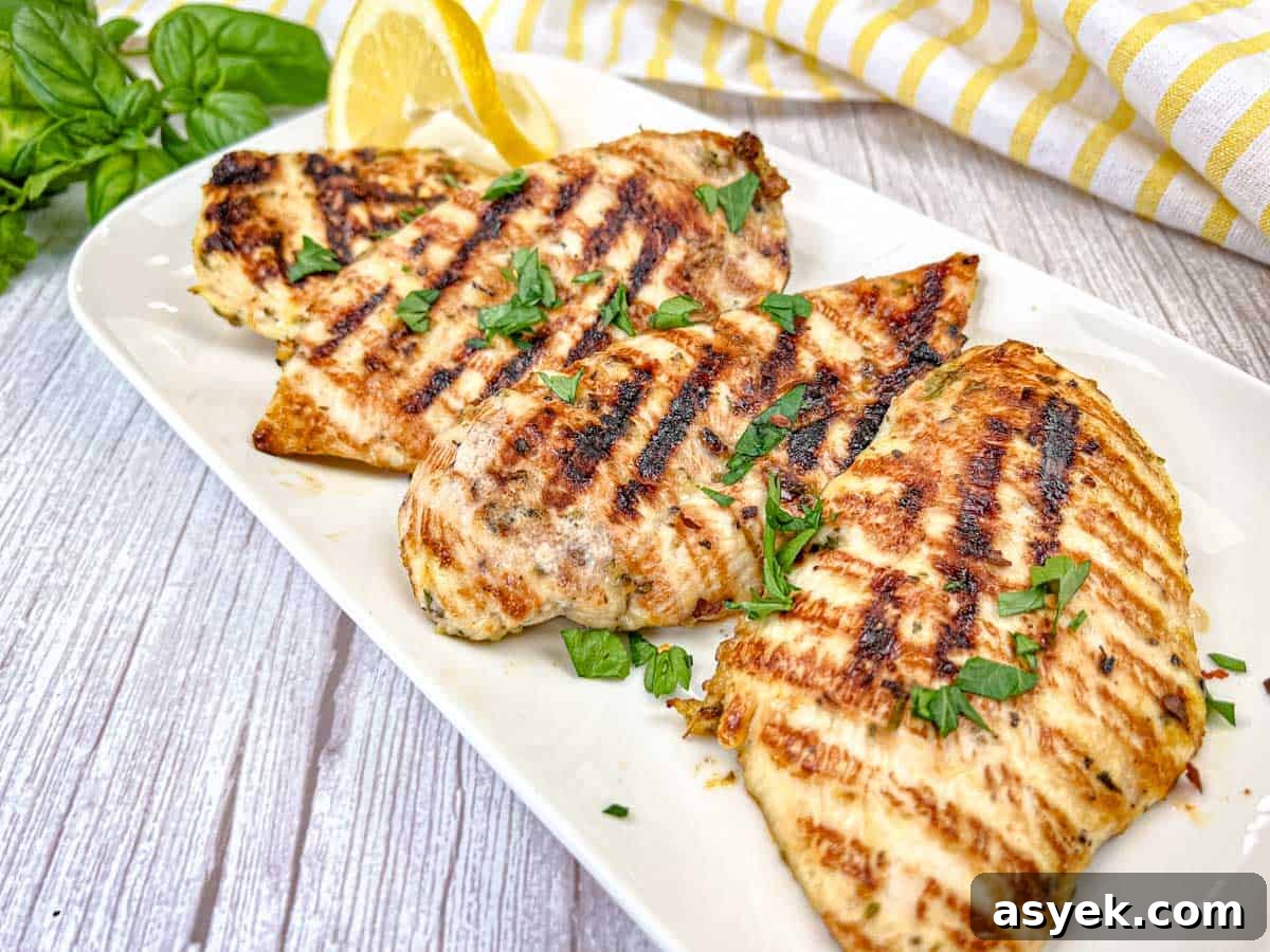 Four pieces of Ninja Woodfire Grill Lemon-Herb Chicken served on a white rectangular plate.