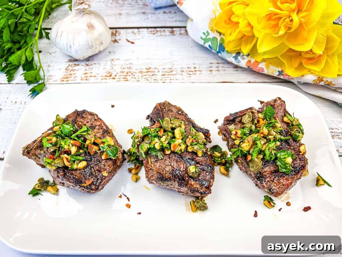 Three Grill Mediterranean Lamb Chops topped with gremolata on a white plate.