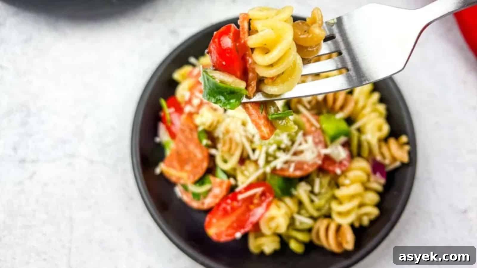 A fork with pizza pasta salad in a bowl.