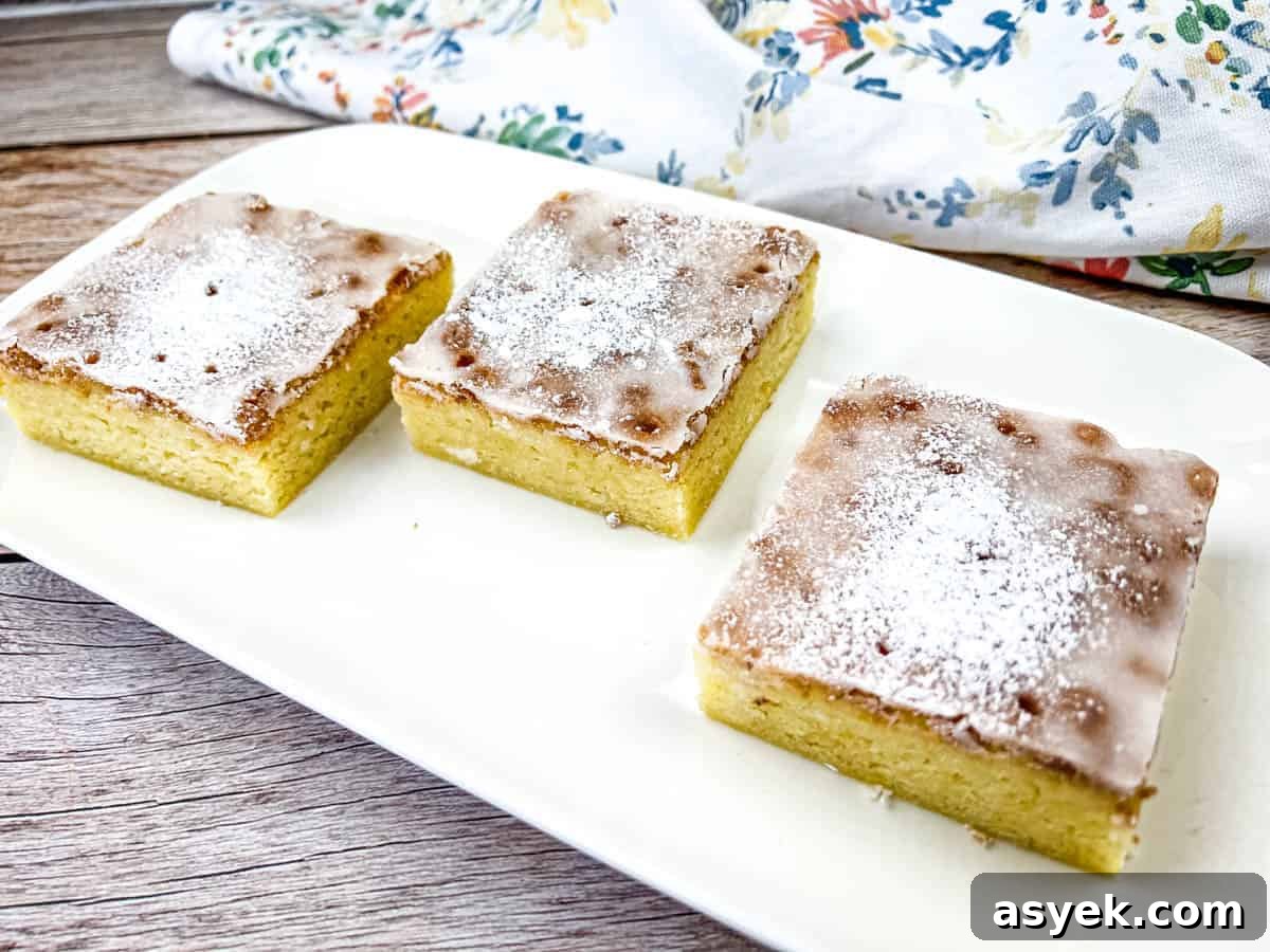 Three square pieces of lemon goldies on a white plate.