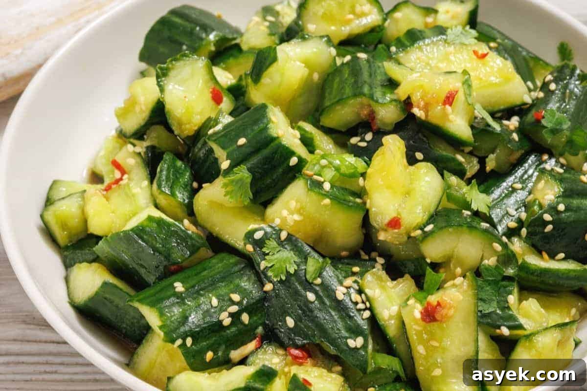 A bowl of smashed cucumber salad with sesame seeds, cilantro, red chili flakes, and a light dressing.