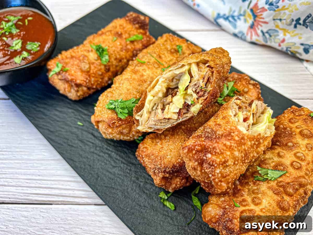 Redneck Eggrolls on a black slate garnished with chopped herbs and a small bowl of dipping sauce.