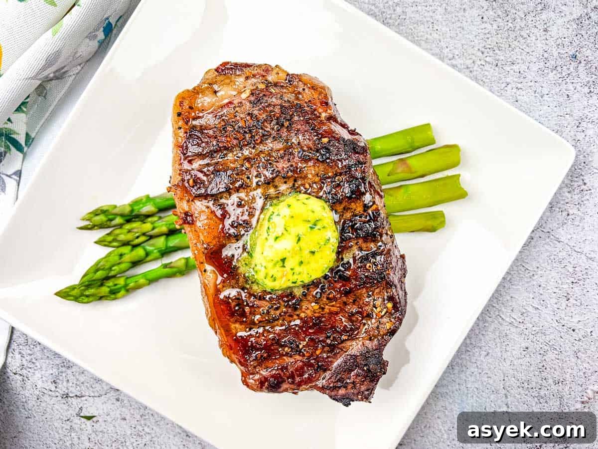 Reverse Seared Smoked Steaks with Smoked Garlic Butter on a plate with asparagus.
