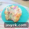 25+ Dairy-Free, Gluten-Free Protein Desserts 19 Vanilla protein cupcake with frosting and sprinkles on a blue cupcake liner with more cupcakes behind it.