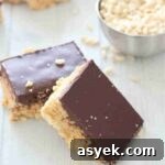 25+ Dairy-Free, Gluten-Free Protein Desserts 3 Two squares of protein rice krispies topped with chocolate leaning on each other and more in the background.