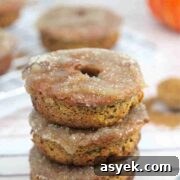 25+ Dairy-Free, Gluten-Free Protein Desserts 22 Three gluten-free pumpkin donuts stacked on top of one another with more donuts in the background.