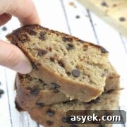 25+ Dairy-Free, Gluten-Free Protein Desserts 23 Two fingers placing a slice of chocolate chip protein banana bread on top of other pieces.