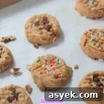 25+ Dairy-Free, Gluten-Free Protein Desserts 25 Small protein cookies topped with sprinkles and chocolate chips on a parchment paper lined baking sheet.