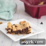 25+ Dairy-Free, Gluten-Free Protein Desserts 28 Square of protein blondies on a white plate with chocolate chips around it.