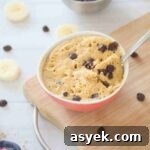 25+ Dairy-Free, Gluten-Free Protein Desserts 36 Mug cake with chocolate chips in a red bowl with a spoon in it on a cutting board.