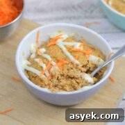 25+ Dairy-Free, Gluten-Free Protein Desserts 39 Carrot mug cake in a white ramekin with a spoon in the ramekin and cream cheese frosting on top.