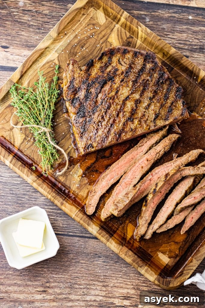 sliced cast iron cooked flank steak on a wooden cutting board