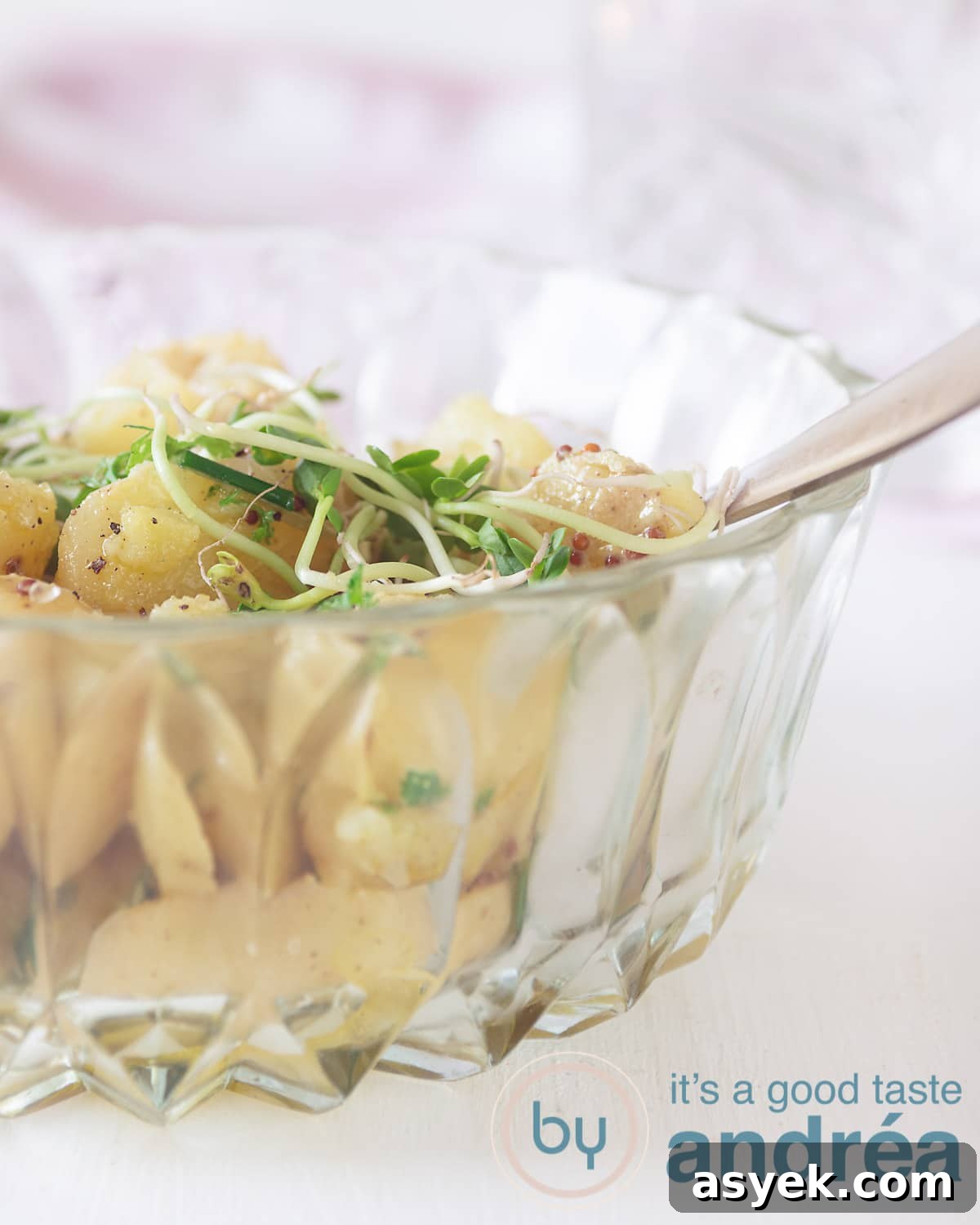 Half a glass bowl filled with new potatoes served as a salad. A white backdrop.